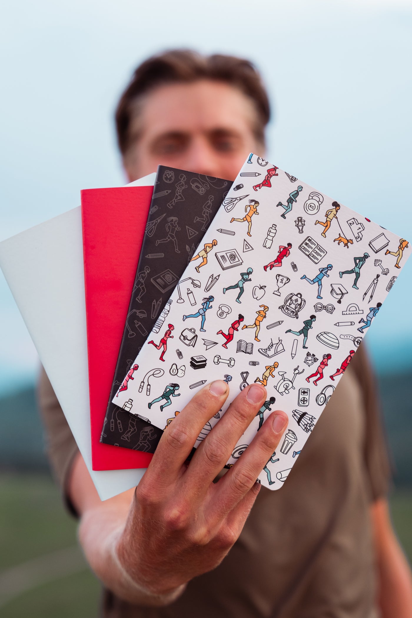 A person holding four running journals.